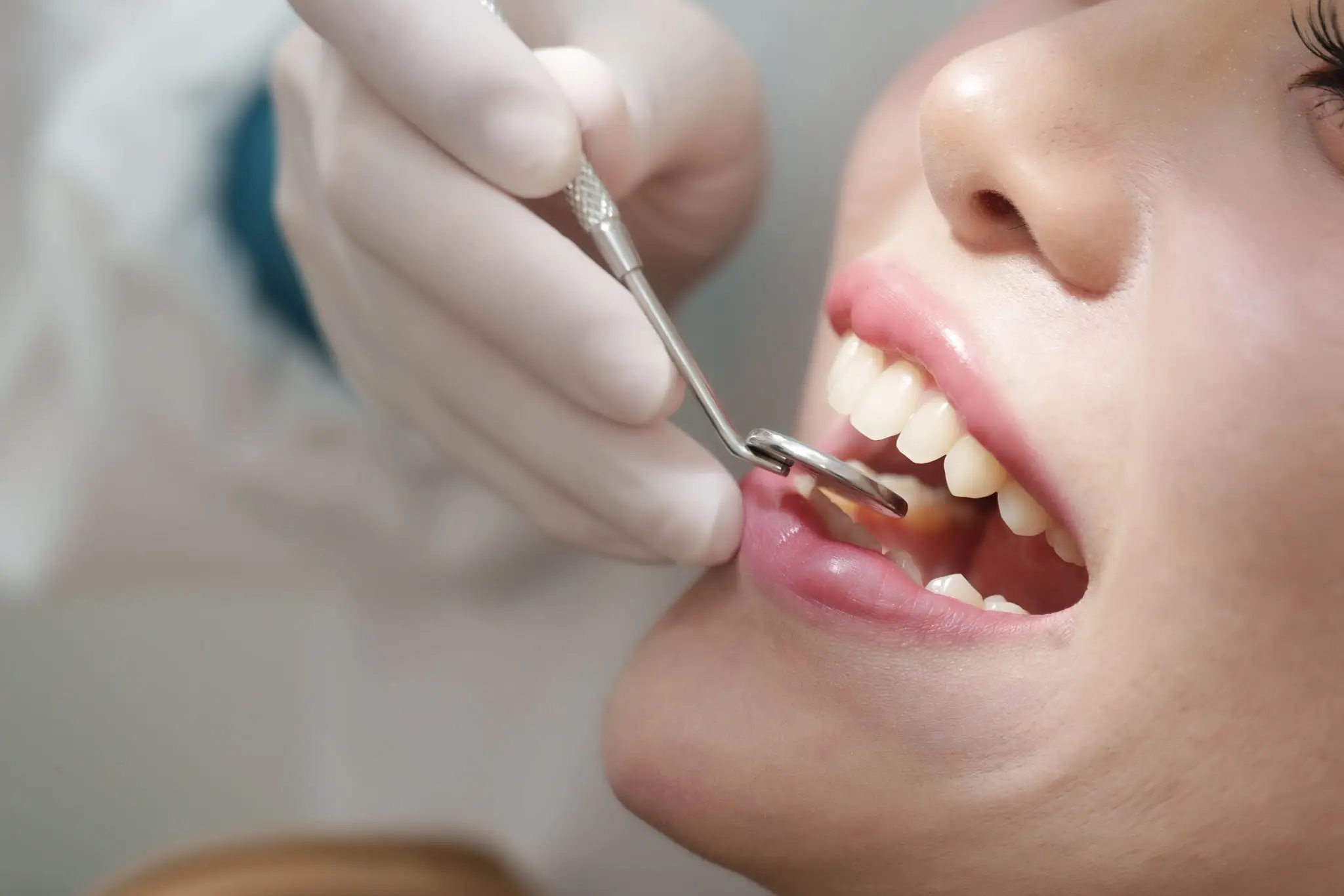 Dentist examining patient's teeth with dental mirror